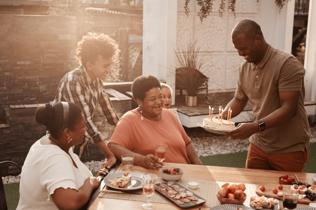 A grandmother, surrounded by children and grandchildren, getting a cake on her birthday.