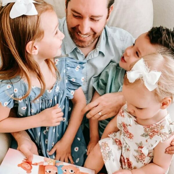 A father sits with his three children as they read a Hooray Heroes personalized book. the best Father's Day gift.