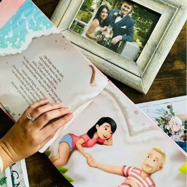 A woman's hand holds open a personalized love you book next to her wedding photo.